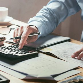 man using a calculator for cross-border payments